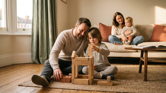 A parent and child building Lego on a wooden floor, both looking down at the bricks rather than each other