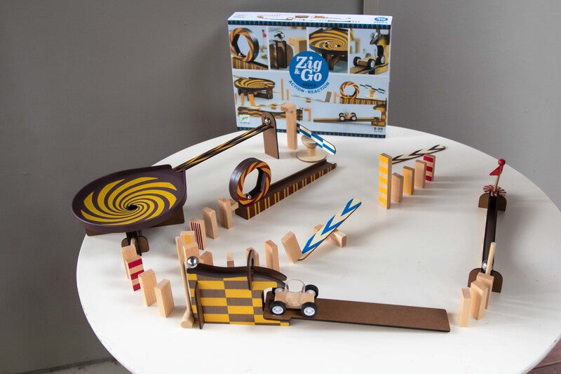 Toy track set with wooden cars and Zig Go packaging on a white surface.