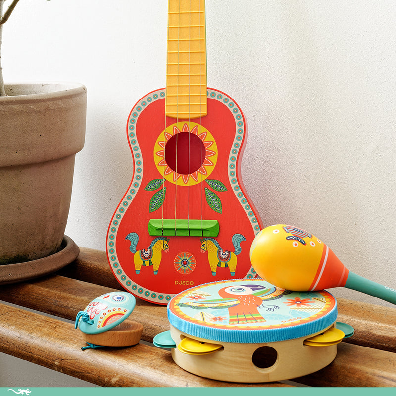 Colorful children's musical instruments including a guitar, maracas, and tambourine on a wooden surface.