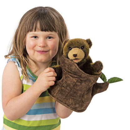 Child holding a teddy bear in a tree-shaped pouch on a white background
