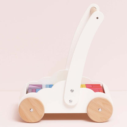 White and wooden toy cart with colorful blocks on a light pink background