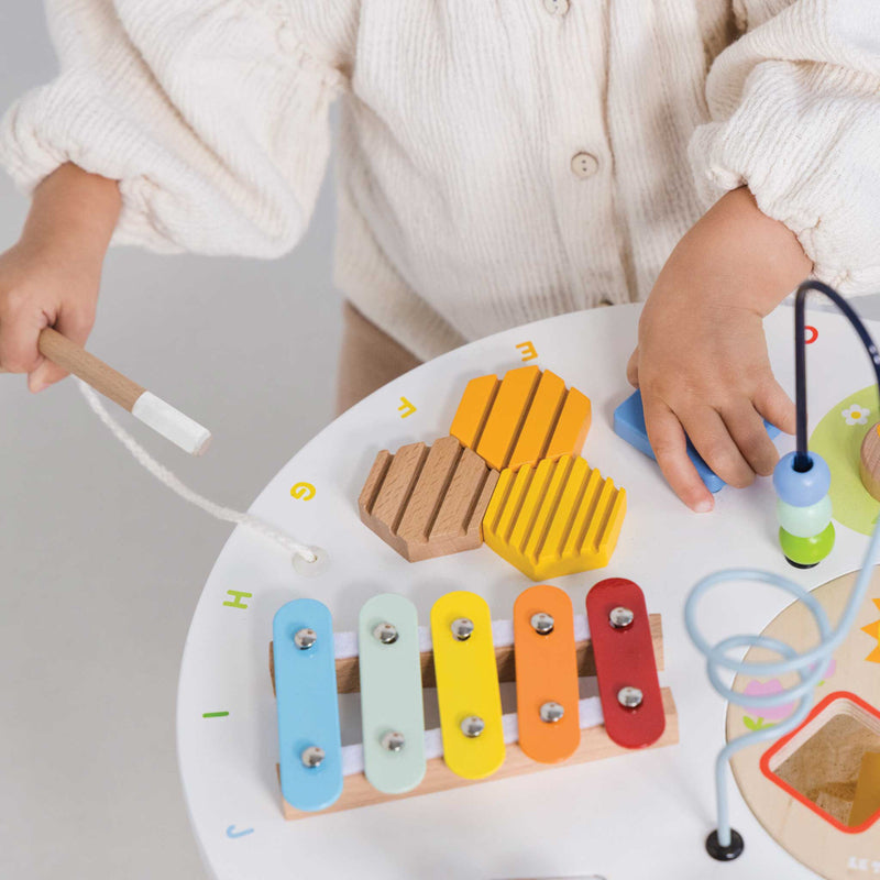 Child playing with a colorful wooden toy on a white surface