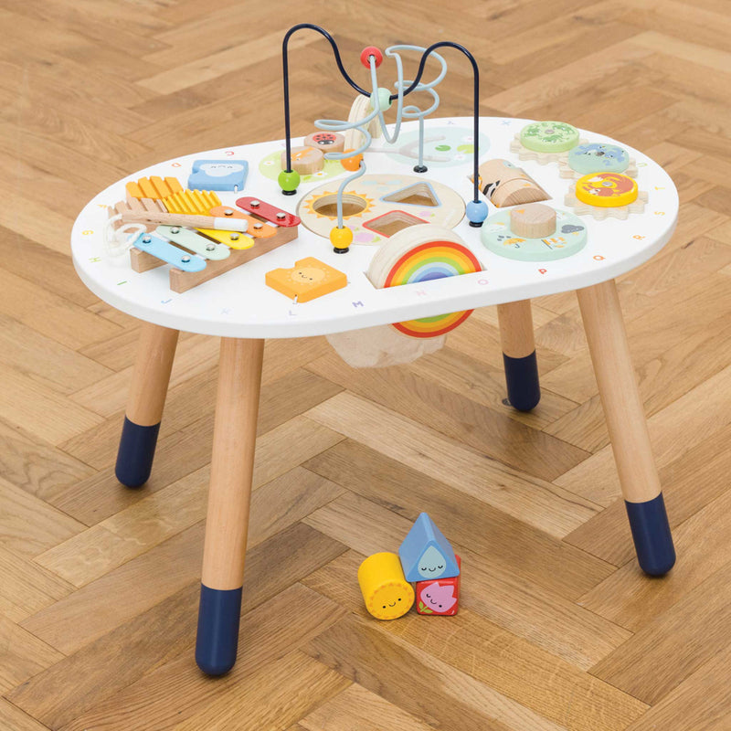 Children's activity table with various toys on a wooden floor