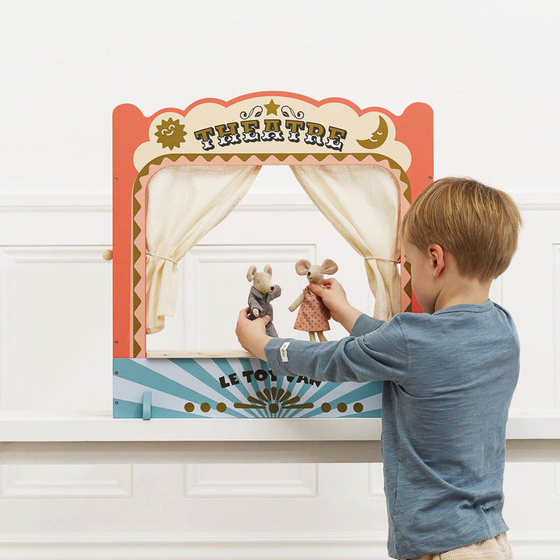 Child playing with a puppet theatre set against a white wall.