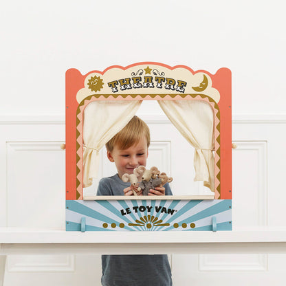 Child holding teddy bears behind a vintage-style 'Theatre' prop with 'Le Toy Van' branding.