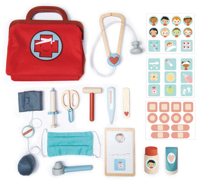 Collection of toy medical tools and accessories including a red bag with a cross, stethoscope, and various pretend medical items on a white background.