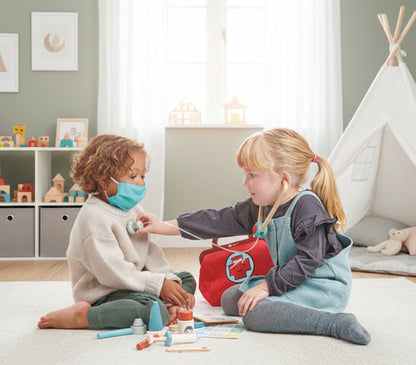 Two children playing with a toy doctor set on a light blue background