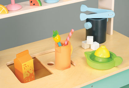 Children's play kitchen set with toy sink, cups, and utensils on a wooden surface.