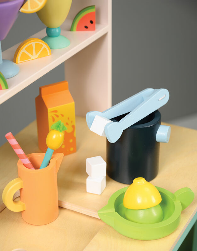 Colorful toy kitchen set on a wooden surface with shelves in the background.