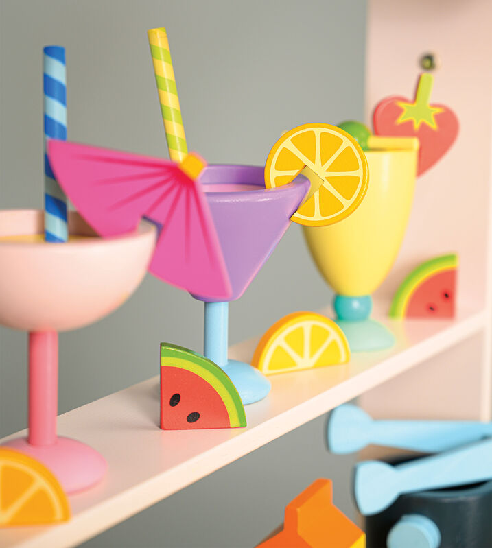 Colorful toy drink set with umbrellas and lemons on a shelf.