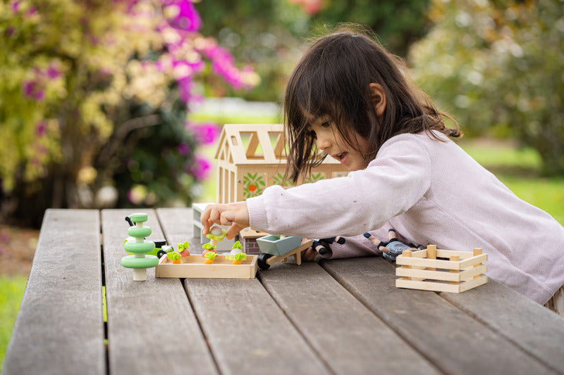 Child playing with wooden toys on a wooden table outdoors
