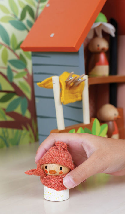 Small figurine of a character wearing a red hat and scarf, held by a hand with a colorful background.