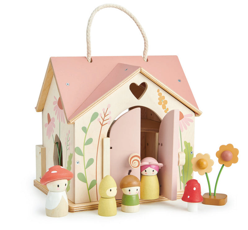 Wooden fairy house with peg dolls and flowers on a white background