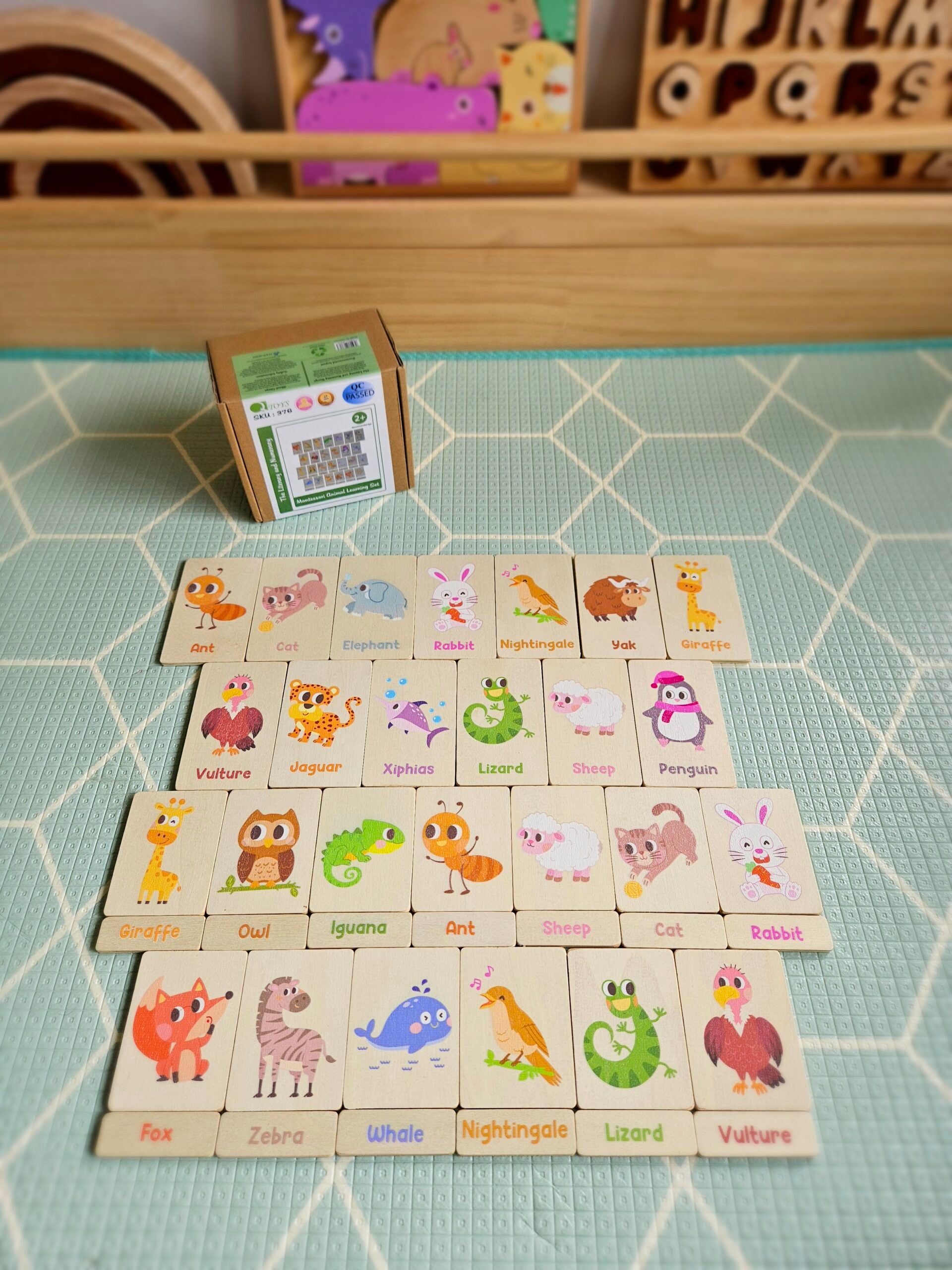 Set of animal-themed wooden blocks on a green tiled surface with a small box in the background.